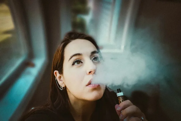 人物手持電子煙裝置並吐出蒸氣